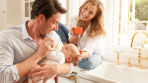Parents bottle feeding baby Munchkin branding